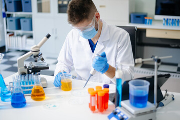 male scientist working with micro pipettes analyzing biochemical samples, advanced science chemical...
