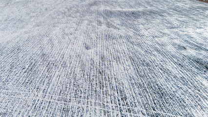 Drone view over a snow covered agriculture field with cultivated rows from crops.