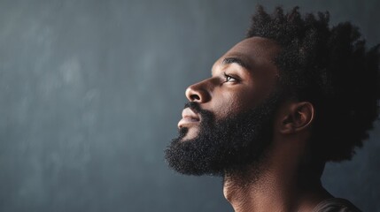 A man with a beard and mustache looking up against a dark background.