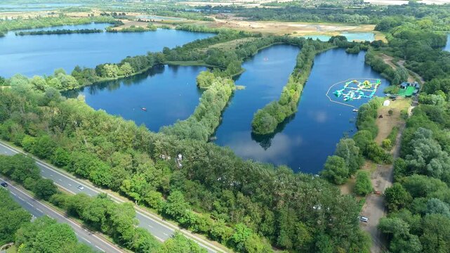Aerial drone shot beautiful blue lakes and lush greenery with aqua water park play event near Little Paxton England UK