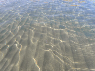 Dark blue ocean surface seen from underwater. Abstract waves underwater and rays of sunlight shining through, Sun light rays undersea deep, Underwater background with sea bottom, Mediterranean sea.