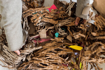 Hands Sorting Pile Of Shredded Cardboard And Paper, Preparing For Recycling