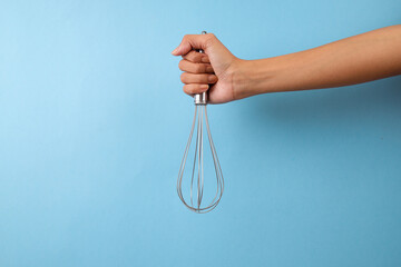 Female Hand Holding Whisk For Mixer Isolated On Blue Background
