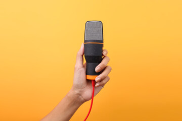 Hand Holding Microphone For Audio Recording Isolated On Yellow Background
