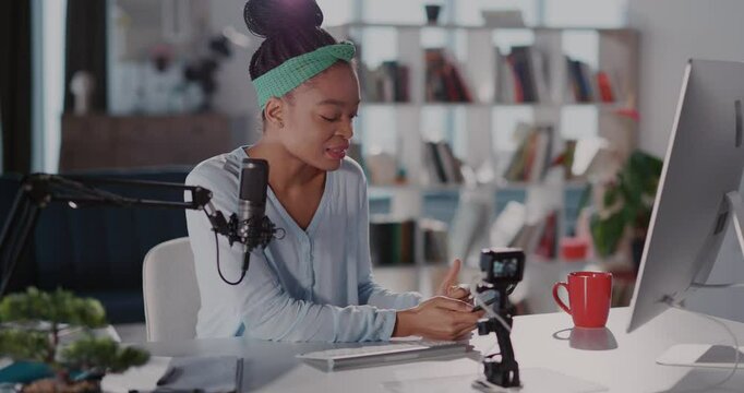 African american casual woman staying home vlogging online tutorial lifehack vlog talking with people communicating radio hosting in living room.