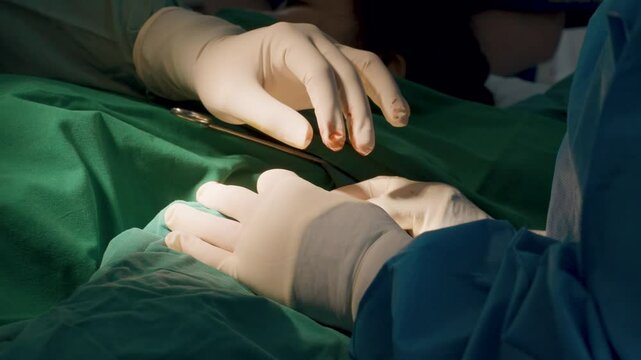 Surgeon's gloved hands perform heart surgery under sterile conditions, with careful precision and focused lighting in the operating room.