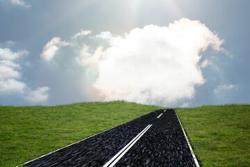 Asphalt road is climbing green grass hill in flat design, displaying dashed lines and clouds