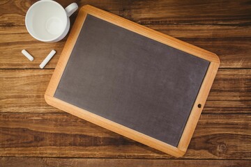 Flat design showing wood-frame chalkboard on wood-grain tabletop with chalk sticks, ceramic mug