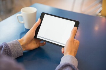 Person is holding tablet with blank screen in flat-design coffee shop scene, with mug nearby © vectorfusionart