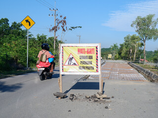 banner with the words HATI-HATI SEDANG ADA PEKERJAAN JALAN/PROYEK in English BE CAREFUL THERE IS...