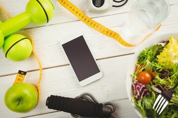 Overhead view of mobile phone and tape measure on wooden table