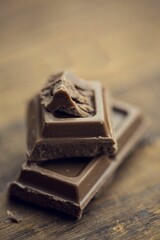 Two milk chocolate squares are sitting stacked on rustic wooden tabletop in 3D render, crumb detail