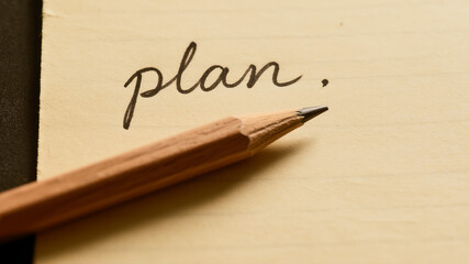 Close-up of 'Plan' Script on Paper with Pencil for Strategic Planning and Goal Setting Concept