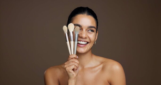 Happy woman, makeup and beauty with brushes in studio for cosmetics on a brown background. Female person, model or smile with product tools for cosmetology, foundation or blending shade on space - Powered by Adobe