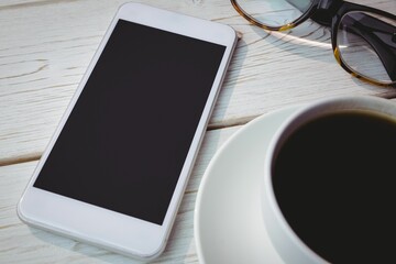 Flat design smartphone showing blank screen is lying on tabletop with coffee cup and glasses nearby © vectorfusionart