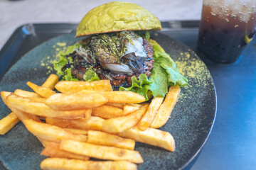 Gourmet burger with fries and a drink on a stylish plate.