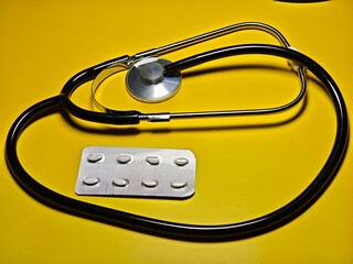 stethoscope and medicine pill on a yellow background