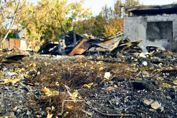 Fire at a car dismantling yard: scorched earth, a concrete house without windows and damaged car...