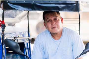 Close-up of a Filipino tricycle driver with squinting eyes, raised brows, and a direct intimidating...