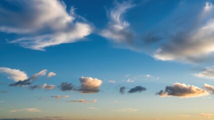 A serene sky with fluffy white clouds scattered across a vibrant blue canvas, hinting at the calm before sunset.