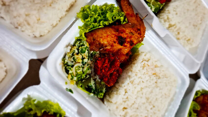 lunch box consists of grilled spicy chicken wings with rice