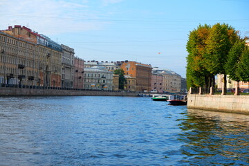 Obraz premium A vibrant boat tour through St. Petersburg's canals, showcasing historical architecture, bridges, and city life under a clear sky
