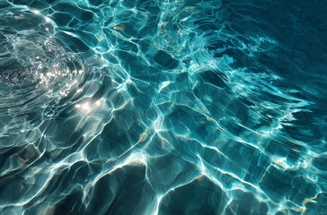 Fototapeta premium Top view of blue and green water in a swimming pool with ripples and sunlight reflections. Background, banner, summer vacation concept.