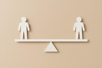 Two paper figures on opposite ends of a seesaw, perfectly balanced. Representing work-life balance, negotiation, or equilibrium in partnership