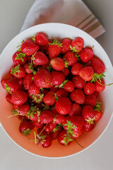Fresh sweet strawberries in a white bowl on a white background. Seasonal berries.