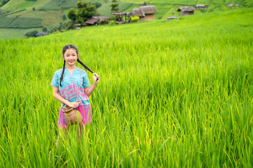 Pretty teenage travellers wearing custom-made Karen dresses in a natural green terraced rice fields at Pa Bong Piang rice fields, Mae Chaem, Doi Inthanon, Chiang Mai, Thailand.