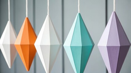 A row of colorful geometric diamond shaped paper lanterns hanging against a soft gray background
