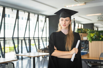 Female Graduate with Diploma Looking Confident, Young Woman in Graduation Cap and Gown Holding...