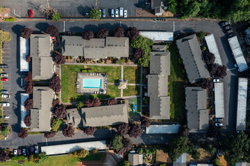 Aerial drone picture of a beautiful residential apartment complex in Gladstone, Oregon, captured at morning. Footage shows green courtyards, swimming pool, parking lots and housing buildings	
