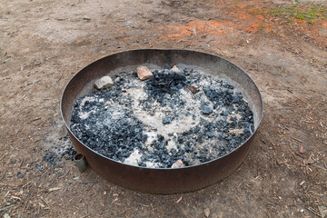 Photograph of a purpose built steel ringed campground fire pit to ensure safe  use for heating and cooking while located in a large forest at risk of bushfire.