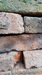 Close-up of old weathered bricks with moss and dirt texture, showcasing rustic surface and natural aging in outdoor condition