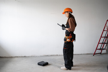 Architect or Inspector Wearing Orange Helmet Holding Clipboard at Construction Site