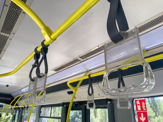 The image shows transparent handrails with black straps suspended from bright yellow poles inside a...
