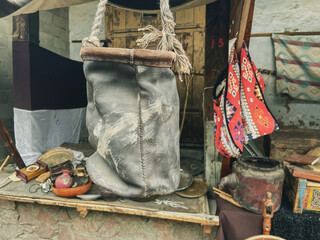 A weathered leather bag hangs from a sturdy rope, surrounded by various antique items. The...