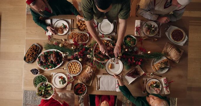 Dishing, people and Christmas dinner in home for festive celebration, event or party together. Food, top view and family in dining room for sharing gourmet meal, feast or supper for xmas in house.