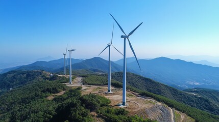 Panoramic view of three wind turbines atop a mountain range under a clear blue sky, generating clean energy