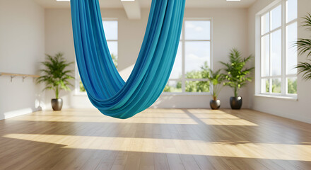 Empty yoga studio with teal fabric hammock, sunlit interior. A relaxing, bright studio space with a hanging yoga hammock and large windows overlooking a garden.