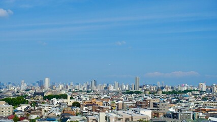 東京の青空を遠くに飛ぶ飛行機