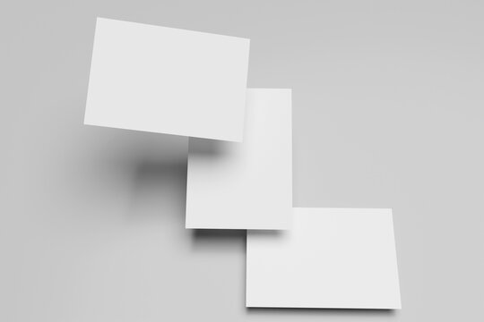 Three white A4 paper, magazine, or business card mockups floating diagonally with soft shadows isolated on grey background.