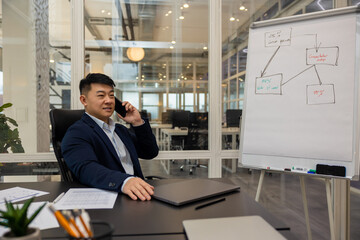 Asian young manager having a phone call and looking busy and involved