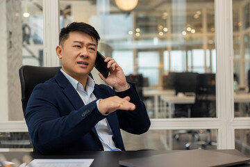 Asian young manager having a phone call and looking busy and involved