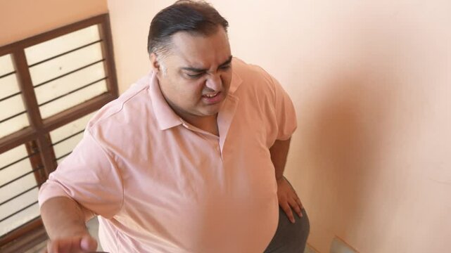 Overweight fat indian man struggle climbing stairs. Plus size guy put effort to lose weight. Obesity and healthcare. 4k