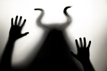 Horror, halloween background - Shadowy figure with horns behind the glass