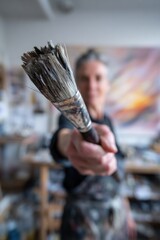 Artist Holding Paintbrush in Bright Studio with Colorful Artwork