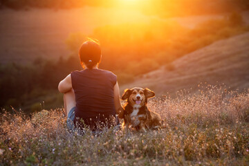 Young woman with her dog watching the sunset