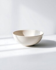 Minimalist creamy bowl on white surface with sunlight and shadow lines